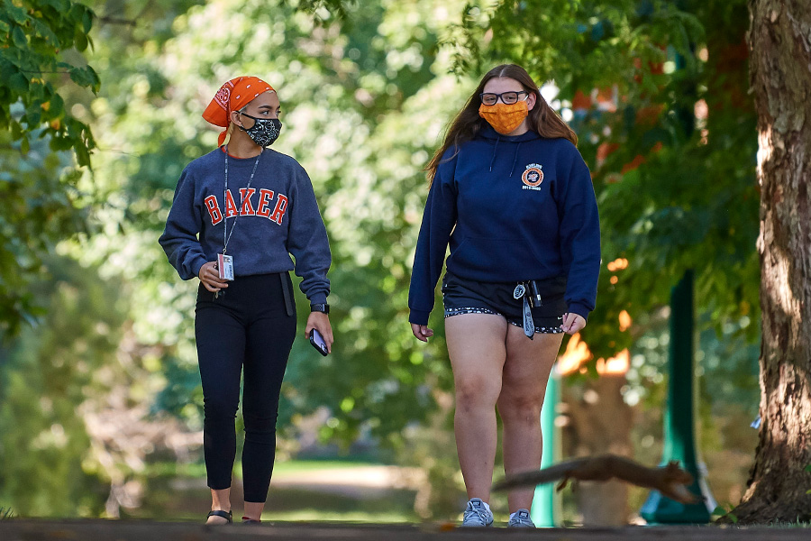 Students walking across campus wearing masks.