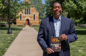 Harold Jackson holding a copy of his book with the chapel in the background